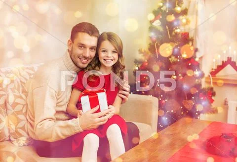 Smiling father and daughter holding gift box Stock Photos