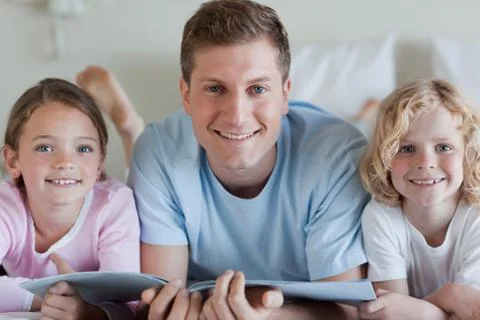 Smiling father with his children and a magazine Stock Photos