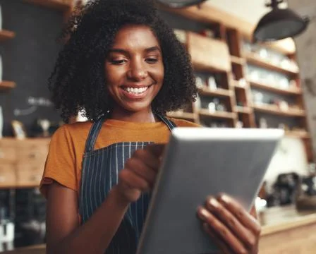 Smiling female cafe owner using digital tablet Stock Photos