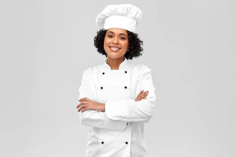 Smiling female chef in white toque and jacket Stock Photos