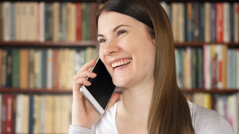 Smiling female college student using cellphone in university library, chatting Stock Footage 87851236