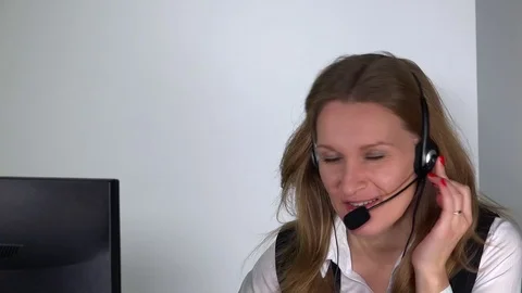 Smiling female consultant assistant with headset looking at camera and computer Stock Footage