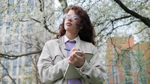 Smiling female designer making notes enjoying nature standing near tree. Video stock 193560214
