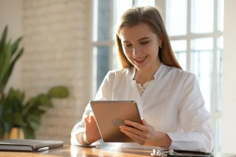 Smiling female doctor consult patient on tablet Stock Photos