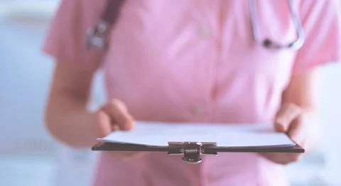 Smiling female doctor with a folder in uniform standing at hospital Stock Photos