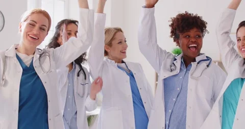 Smiling female doctors stacking hands, clapping, showing unity and teamwork 動画素材 304867820