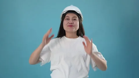 Smiling Female Engineer Putting On Hard Hat Helmet Against Blue Background Video stock 346111548