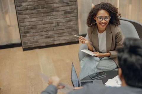 Smiling female manager is making notes during meeting with colleague in Stock Photos