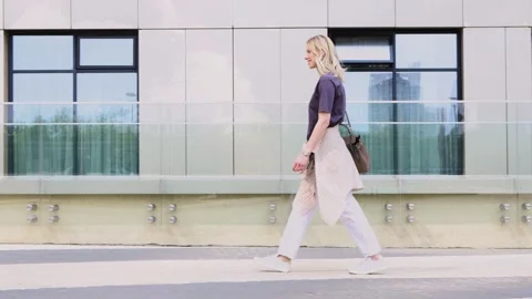 Smiling female model looking at camera while walking outdoors in city Stock Footage 328225637
