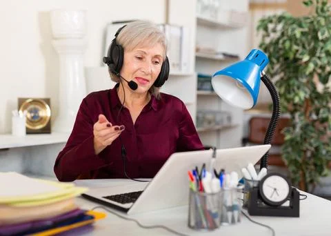 Smiling female operator talking with customer using headset at office Stock Photos