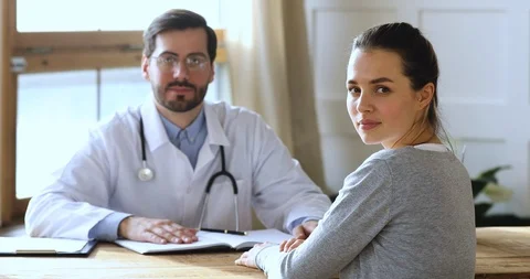 Smiling female patient looking at camera visiting male doctor, portrait Stock Footage