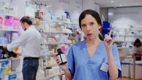 Smiling female pharmacist offers useful medical products in a pharmacy Stock Footage