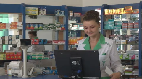 Smiling female pharmacist working on desktop, papers in hand pharmacy pills view Stock Footage 40664771