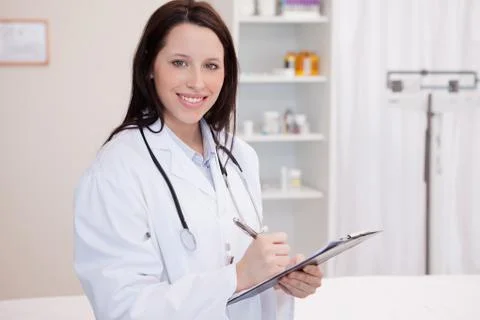 Smiling female physician taking notes Stock Photos