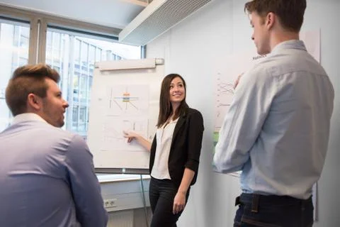 Smiling Female Professional Explaining Chart To Colleagues Stock Photos