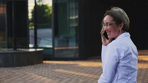 Smiling female professional talking on smart phone outside office building Stock Footage 166457780