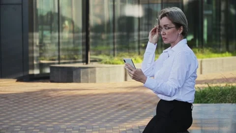 Smiling female professional talking on smart phone outside office building Stock Footage 166457971