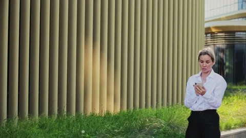 Smiling female professional talking on smart phone outside office building Stock Footage 166458218