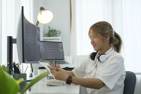 Smiling female programmers sitting front of large curved  computer monitor .. 스톡 사진