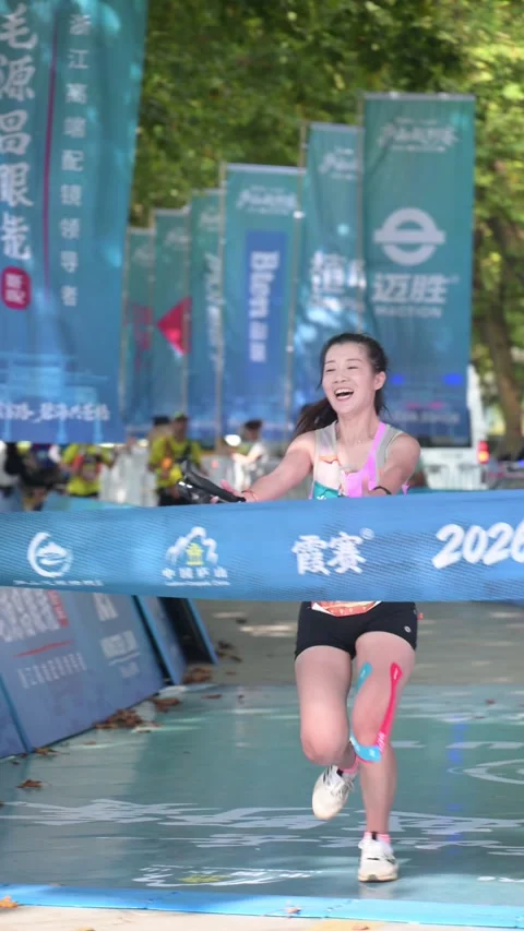 Smiling Female Runner Breaking Finish Tape with Arms Open, Lushan Stock Footage 346717147