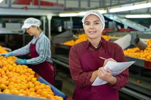 Smiling female shift supervisor with papers at tangerine sorting line Stock Photos