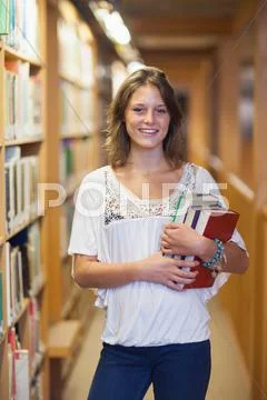 Smiling female student standing in the library Stock Photos