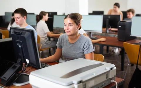 Smiling female student using PC and xerox while studying computer science in the Stock Photos