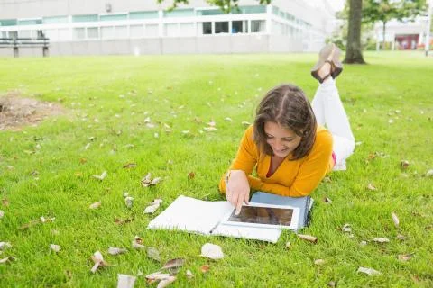 Smiling female student using tablet PC in lawn Foto stock