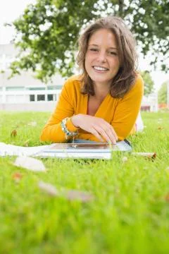 Smiling female student using tablet PC in lawn 写真素材
