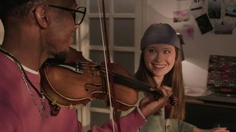 Smiling Female Synth Player Collaborating with Male Violinist in Living Room Stock Footage 335410125