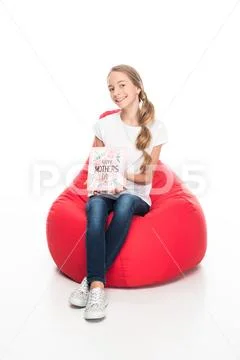 Smiling female teenager holding greeting card for happy mothers day and sitti Stock Photos