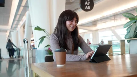 Smiling female traveler using digital tablet at airport gate Stock Footage 334540087