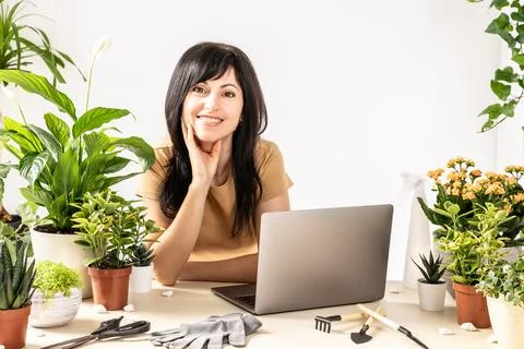 Smiling female using laptop computer at workshop transplantation houseplants Foto stock