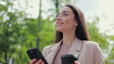 Smiling female using modern gadget while standing in park and holding coffee cup Stock-Footage 275825386