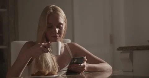 Smiling female using smartphone and drinking coffee Stock Footage 251478385