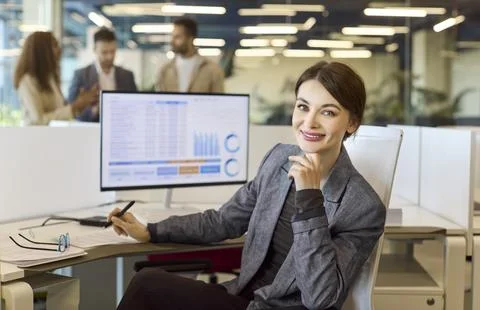 Smiling financial analyst at computer with data charts, office portrait business Stock Photos