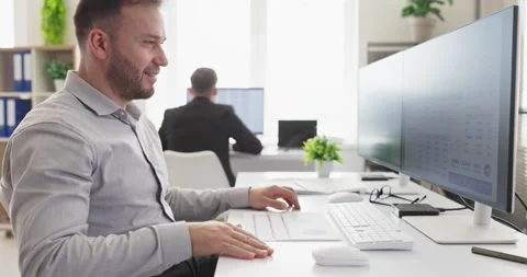 Smiling financial analyst working with data dashboards on computer in bright Stock Footage 345866600