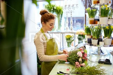 Smiling florist woman making bunch at flower shop Stock Photos