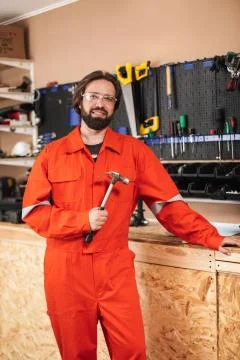 Smiling foreman in orange work clothes and protective eyewear ho Stock Photos
