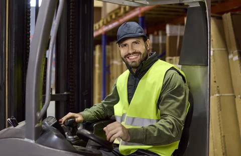 Smiling forklift operator in warehouse focused on safe storage and logistics Stock Photos