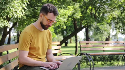 Smiling freelancer in glasses using laptop in park Stock-Footage 136115822