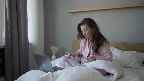 Smiling freelancer with laptop and notepad in bed Stock Footage 139570469