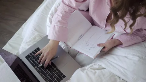 Smiling freelancer with laptop and notepad in bed Stock Footage 139570607