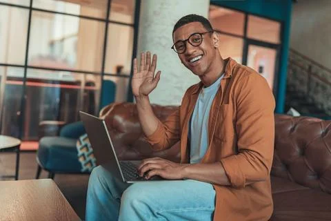 Smiling freelancer working on laptop while sitting in coworking background and Stock Photos