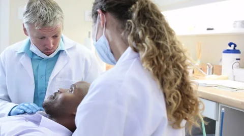 A smiling, friendly dentist talking to and reassuring patient in the chair Stock Footage 54785516