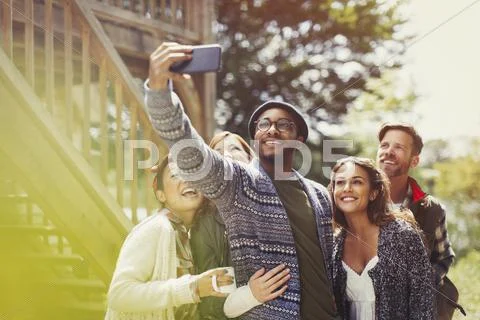 Smiling friends with camera phone taking selfie outdoors Stock Photos