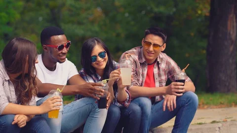 Smiling friends in camus having fun drinking fresh juices Stock Footage 127913068