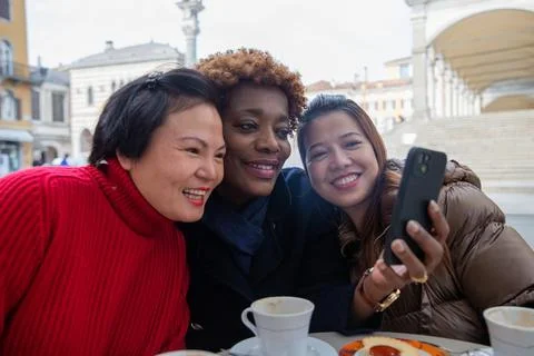 Smiling friends having fun sharing something on the mobile phone. Diversity.. Stock Photos