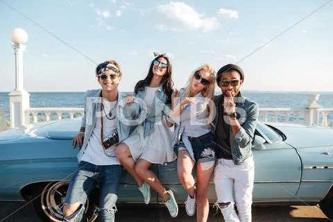 Smiling friends standing and sending kiss near cabriolet Stock Photos