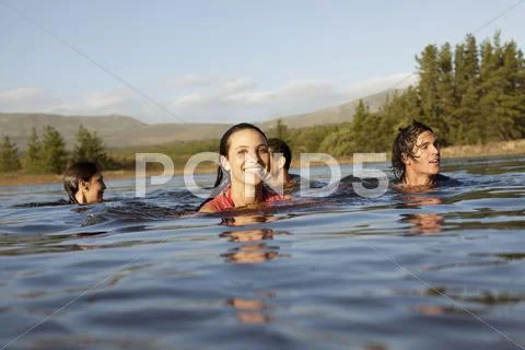 Smiling friends swimming in lake Stock Photos